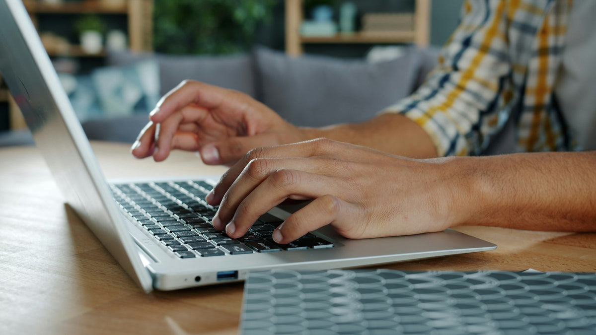 Mains tapant sur un ordinateur portable à un bureau